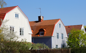 Straße mit schönen alten Einfamilienhäusern mit rotem Walmdach und Fassade mit Holzverkleidung