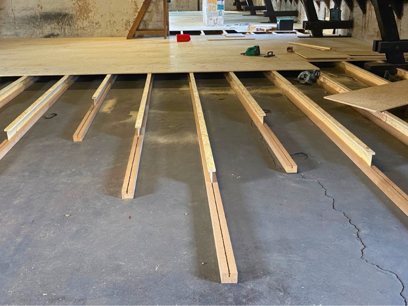 Durch eine Holzkonstruktion, die mit Einblas-Dämmung gefüllt wird, bleibt der Boden begehbar Begehbare Dämmung der obersten Geschossdecke, mit einer Holzunterkonstruktion auf dem Betonboden